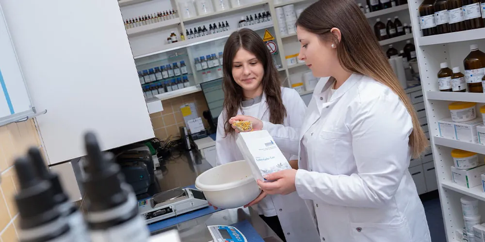 Zwei Mitarbeiterinnen der St. Anna-Apotheke in der Rezeptur mit Reibschale und Tropfflaschen